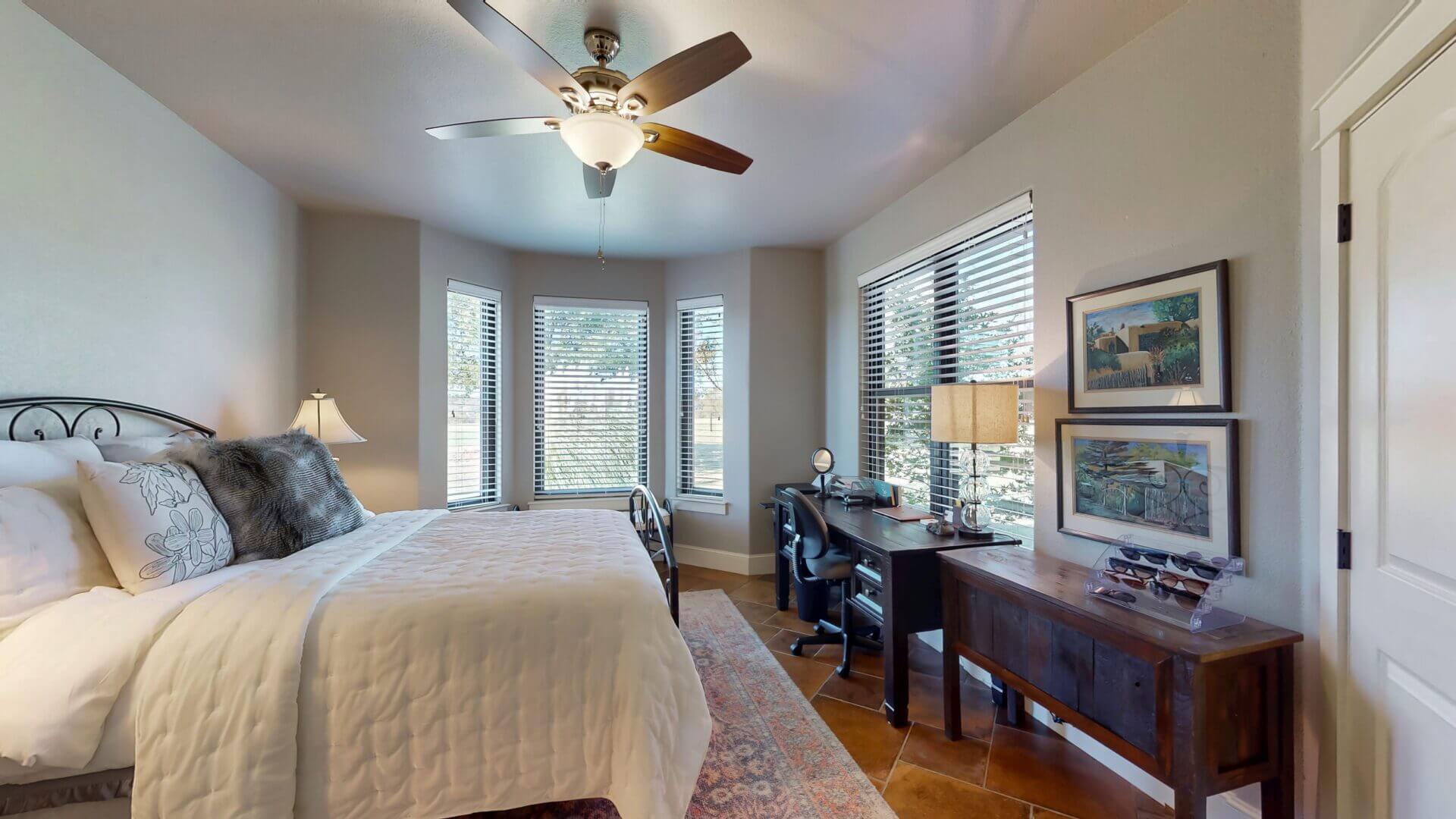 Bright bedroom featuring large windows and desk.