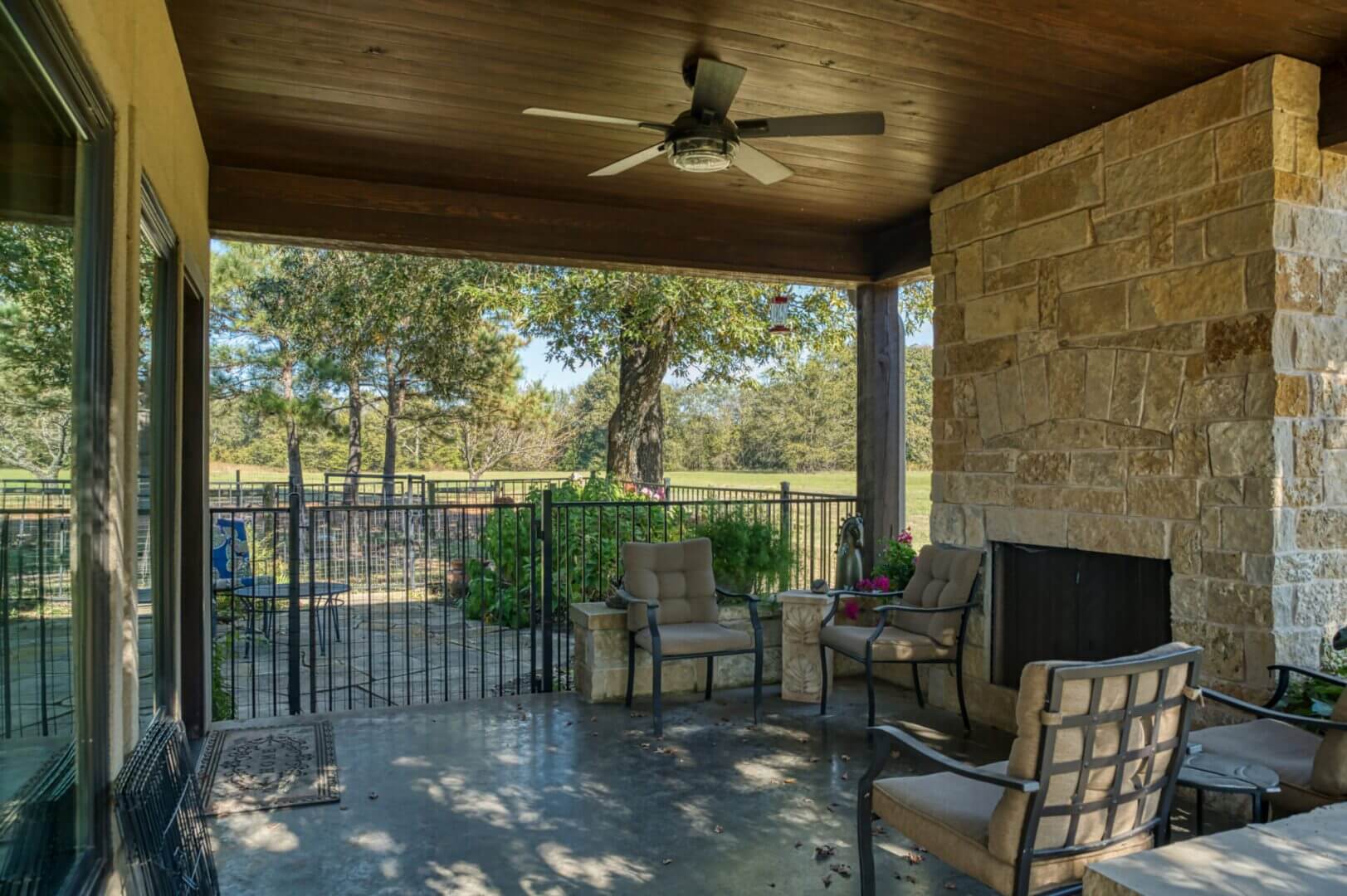 Cozy outdoor patio with comfortable seating and ceiling fan overlooking a scenic garden.