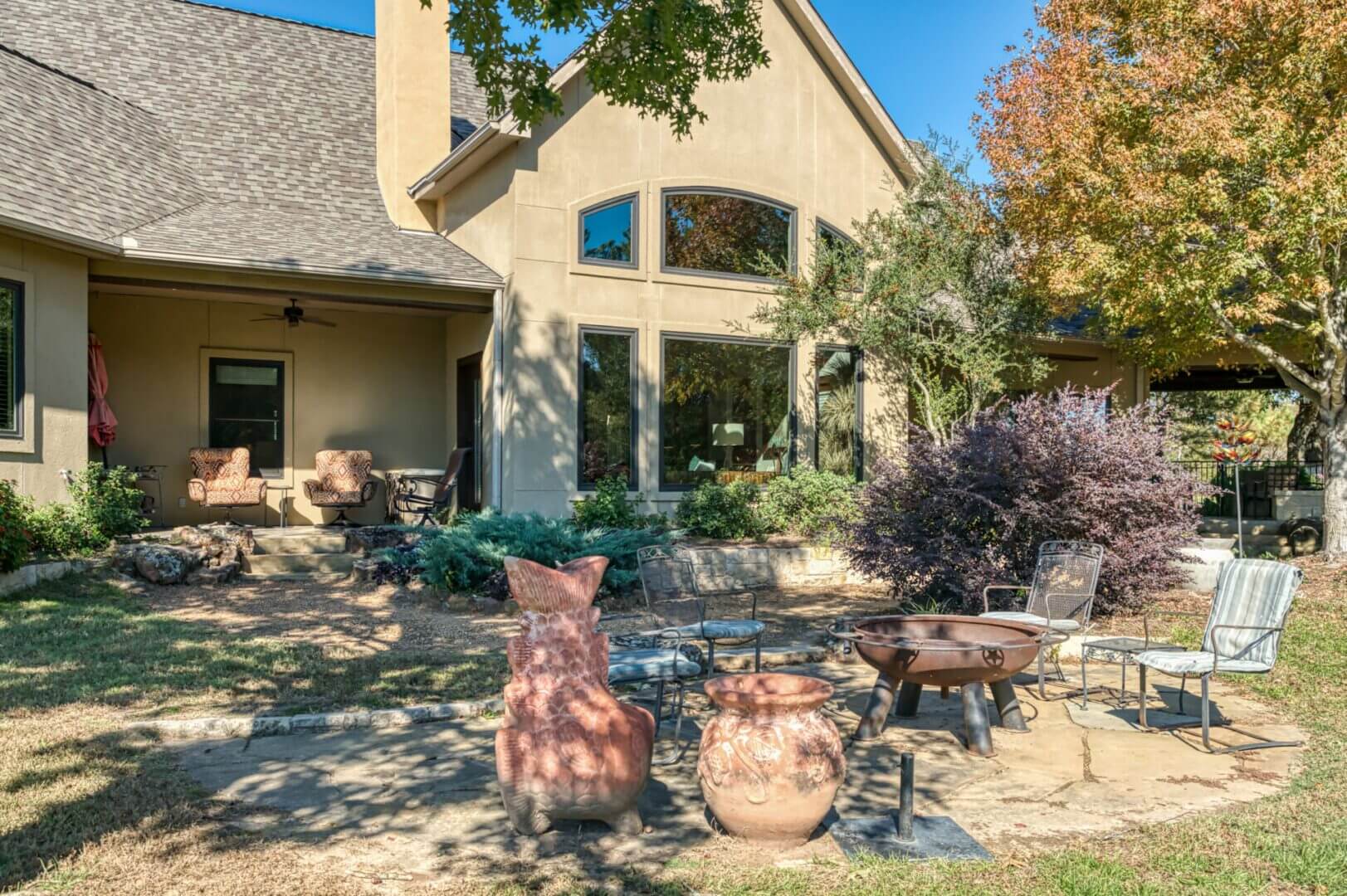 Cozy backyard with rustic pots and a fire pit in front of a house.