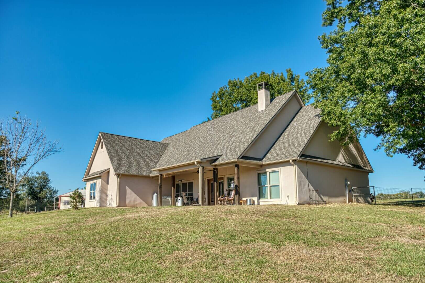A spacious suburban house with a large porch under a clear blue sky.