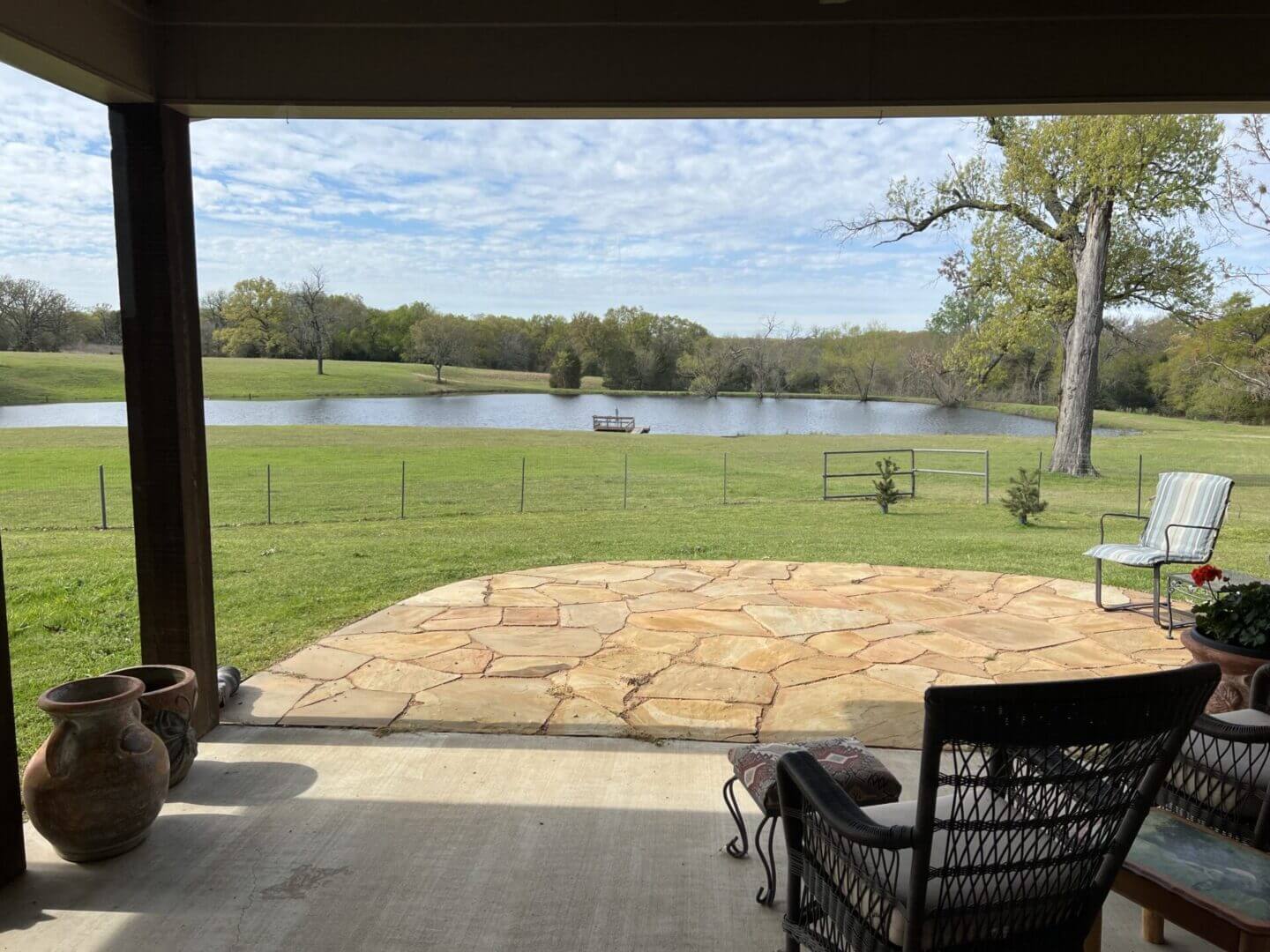 View of a peaceful lake from a shaded patio with a rocking chair.